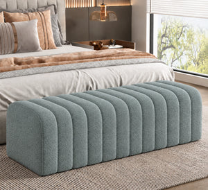Blue grey channel tufted storage ottoman at the foot of a bed