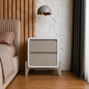 Beige nightstand next to a bed with a textured wall and lamp in the background