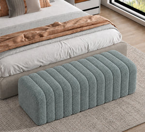 Blue grey channel tufted upholstered ottoman at the foot of a bed