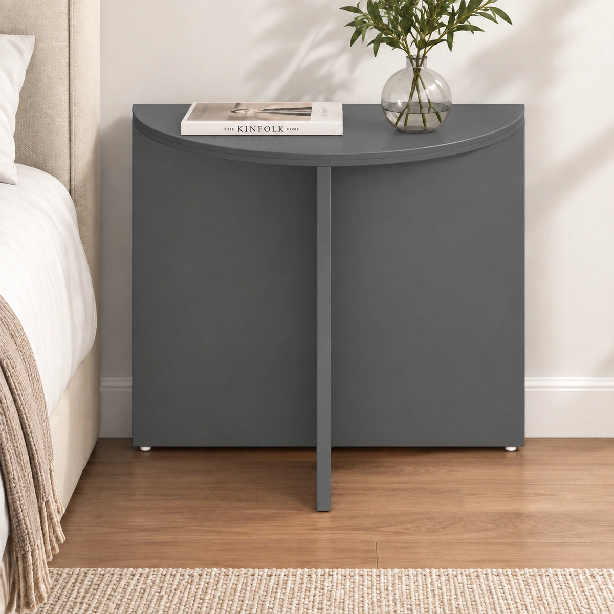 Modern charcoal half moon end table styled beside a bed