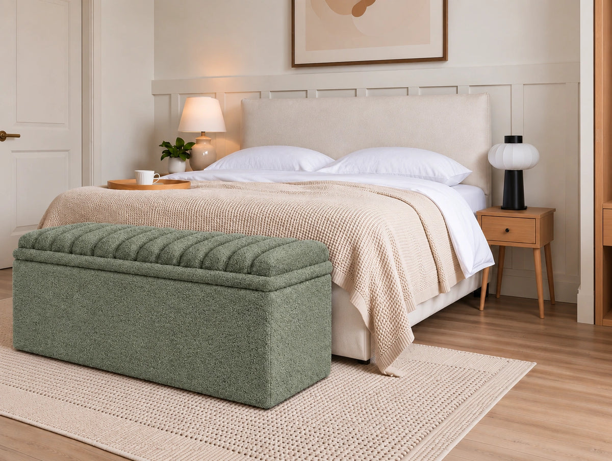 Green upholstered storage ottoman placed at the foot of a bed
