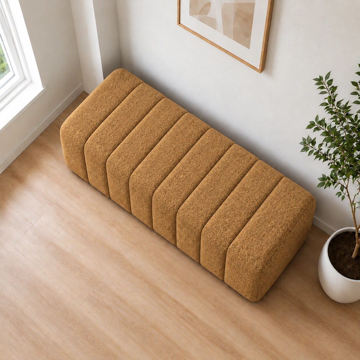 Mustard brown upholstered ottoman shown from a side angle