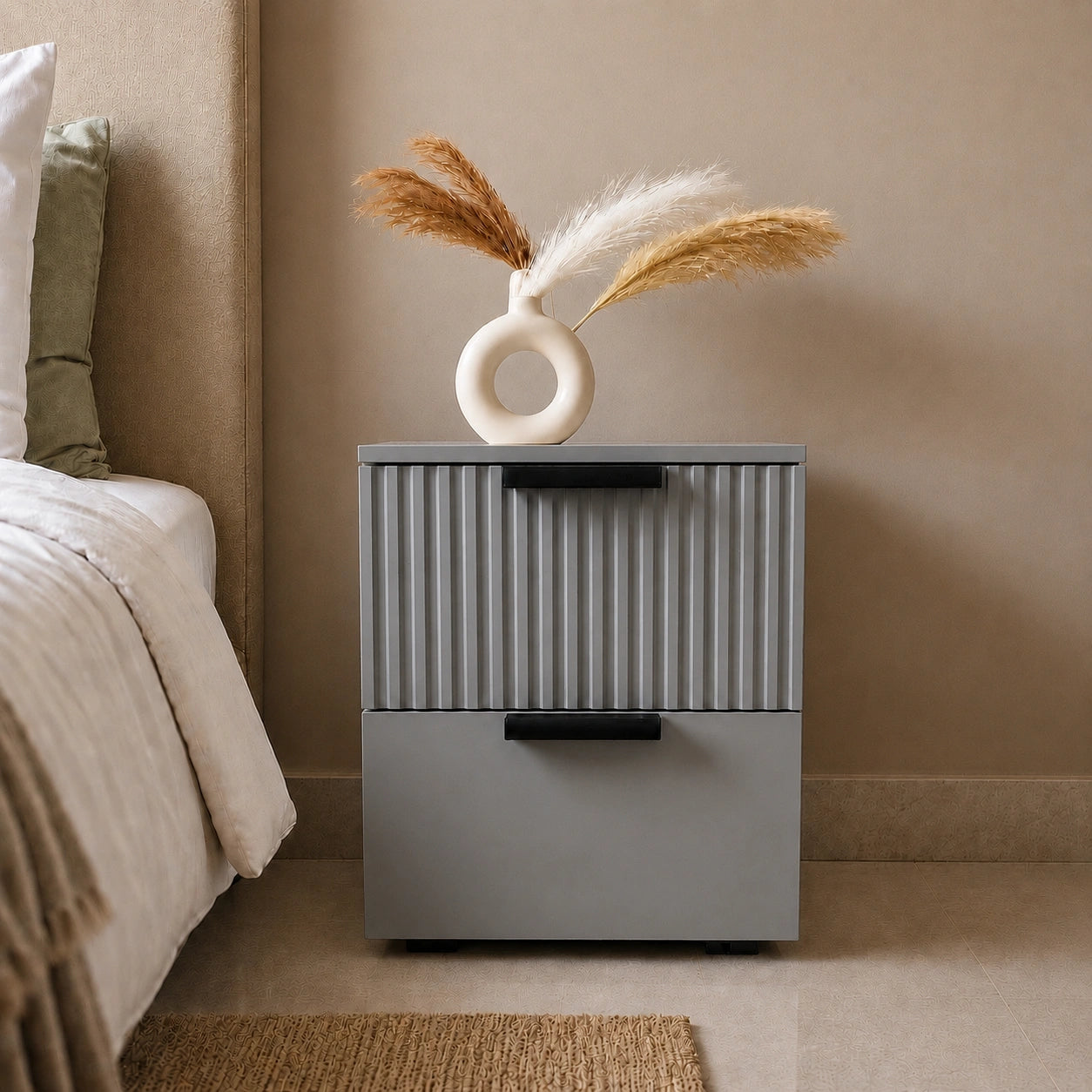 Grey Solid Wood bedside table with fluted drawer design and black handles placed beside a modern bedroom bed.