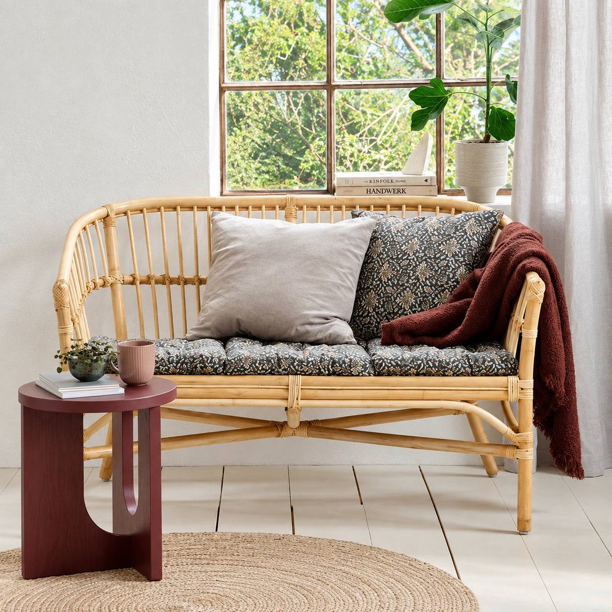 Terracotta round end table next to a rattan sofa